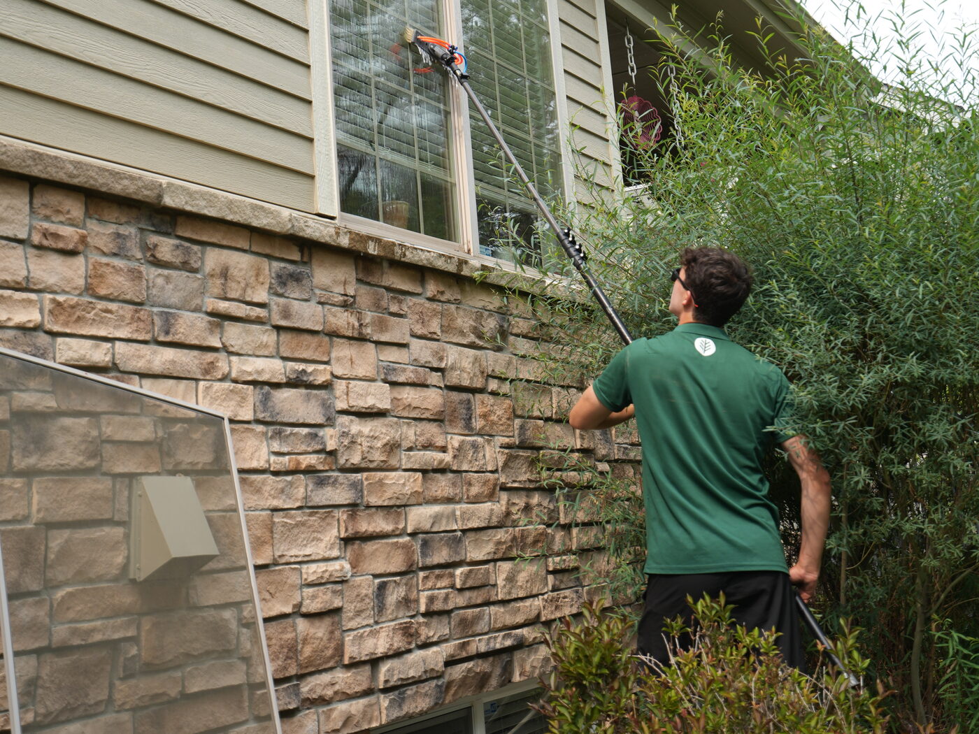 Pine Window Cleaning technician cleaning second-story windows with a water-fed pole